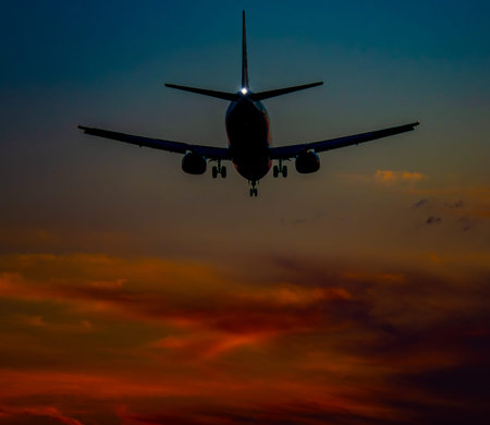 Silhouette of a passenger plane flying in the evening sky.