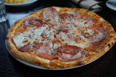a huge pizza with different ingredients on a dark tableの写真素材