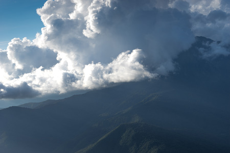 mountain landscape on the blue sky background and white clouds with sun raysの写真素材