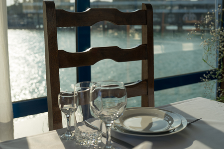 Set the table in the seaside caf with a white tablecloth and glass and crockeryの写真素材