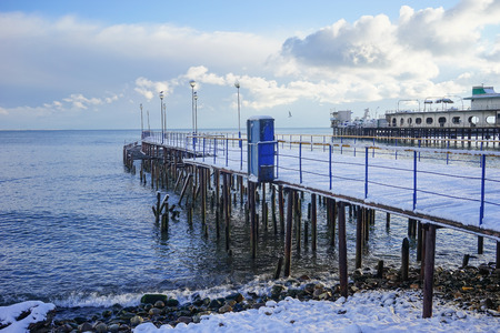 The old jetty is covered with snow by the sea in winter timeの写真素材