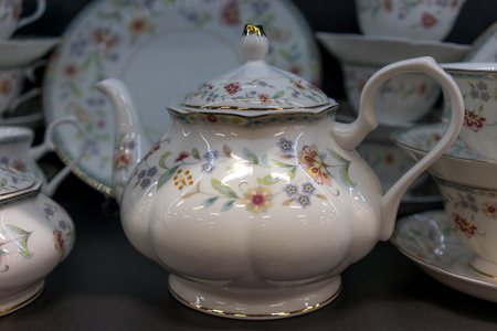 Porcelain teapot in the background of dishes and the dark backgroundの写真素材