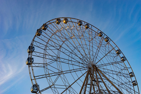 A Ferris wheel with lots of booths in the amusement Park of Sochi on the background of blue sky.の写真素材