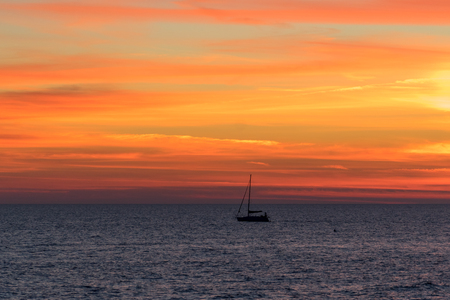 Sochi, Russia, 07 Jan 2018. Seascape with a vibrant sunset over a calm sea and a floating boat.の写真素材