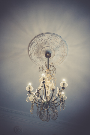 crystal chandelier in vintage style with lots of pendants and lamps on the high ceiling.の写真素材