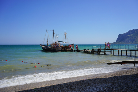 Koktebel, Crimea-June 27, 2015: Tourist ships in an old romantic style on the pier waiting for a group of tourists.のeditorial素材