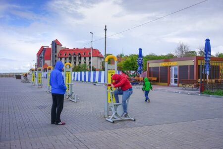 Zelenogradsk, Russia-may 17, 2016: A man with children in multi-colored jackets standing at the public gyms waterfront city.のeditorial素材