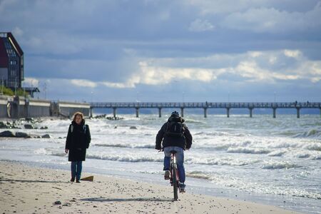 Zelenogradsk, Russia-may 17, 2016: An elderly woman walks along the sandy beach towards the cyclist.のeditorial素材