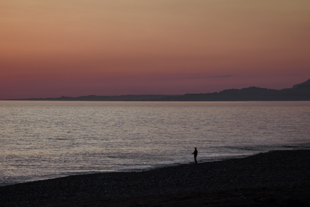 Lonely man fishing on the pier at sunset and calm .の写真素材