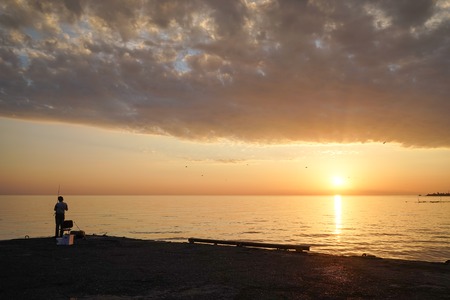 Lonely man fishing on the pier at sunset and calm .の写真素材