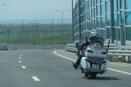 The rider on the white motorcycle racing on the highway to the Crimean bridge.のeditorial素材