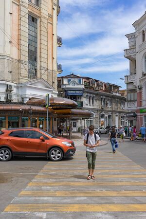 Yalta, Crimea-may 30, 2018: Pedestrian crossing on a city street with a young man.のeditorial素材