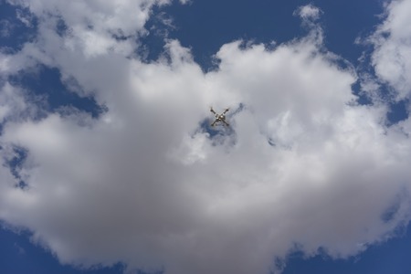 Blue sky with big white cloud and flying quadrocopter.の写真素材