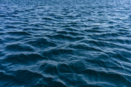 The water surface of the sea is blue with small waves.の写真素材