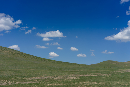 Natural landscape with hills against blue sky with white clouds.の写真素材