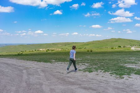 Belogorsk, Crimea-may 22, 2018: The boy runs across the plain towards the hills.のeditorial素材