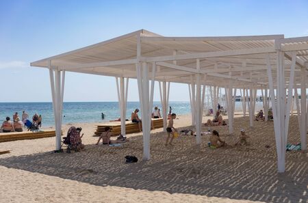 Evpatoria, Crimea-may 23, 2018: The coastline of the city with yellow sand and resting people.のeditorial素材