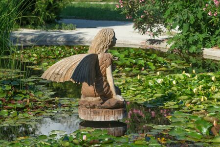 Sochi, Russia-June 24, 2018: landscape with a wooden statue of a fairy in a small pond with water liliesのeditorial素材