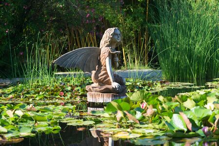 Sochi, Russia-June 24, 2018: landscape with a wooden statue of a fairy in a small pond with water liliesのeditorial素材