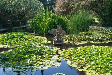 Sochi, Russia-June 24, 2018: landscape with a wooden statue of a fairy in a small pond with water liliesのeditorial素材