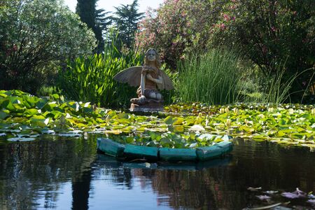 Sochi, Russia-June 24, 2018: landscape with a wooden statue of a fairy in a small pond with water liliesのeditorial素材