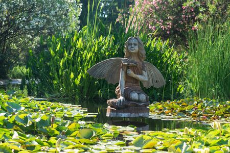 Sochi, Russia-June 24, 2018: landscape with a wooden statue of a fairy in a small pond with water liliesのeditorial素材