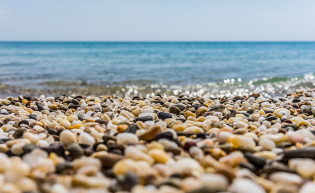Sunny beach on the sea with sand and pebbles under the blue skyの写真素材
