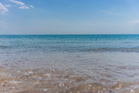 Sunny beach on the sea with sand and pebbles under the blue skyの写真素材