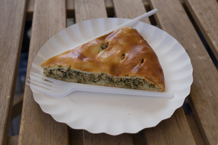 A piece of baked fish cake on a white paper plate with a plastic forkの写真素材