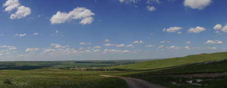 panorama with plain and road under blue sky with cloudsの写真素材