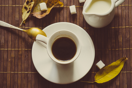 still life with black coffee on a dark background with autumn yellow leavesの写真素材