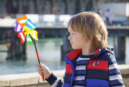 Sukhumi, Abkhazia-April 11, 2014: The child obscures the face with a turntable with bright blades on a blurred background of a city streetのeditorial素材