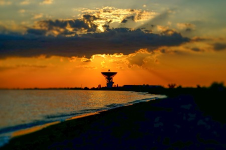 Magnificent sunset on the background of the sea and space antenna. The rays of the sunset illuminate the coastline of the sea in the area of Yevpatoria in the Crimea.の写真素材