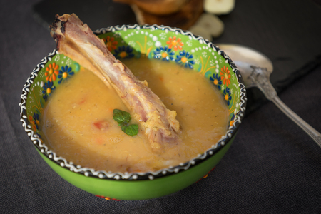 red lentil soup with smoked ribs in a light green bowl with floral ornament. Dark grey fabric background.の写真素材