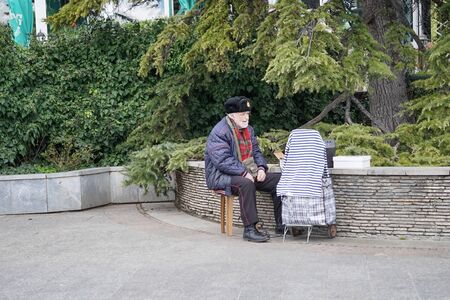 Yalta, Crimea-March 13, 2015: An elderly man sitting on the waterfront of the city with a musical installation.のeditorial素材
