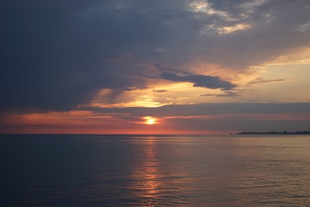 Amazing sunset on the ocean. View of dramatic cloudy sky and reflection of the sunlight on water.の写真素材