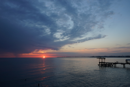 Amazing sunset on the ocean. View of dramatic cloudy sky and reflection of the sunlight on water.の写真素材