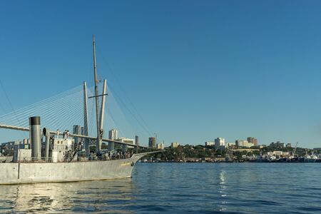 Vladivostok, Russia-September 9, 2018: City landscape with ships and Golden bridge on blue sky background.のeditorial素材