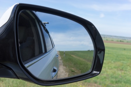Car mirror on a background of green fields.の写真素材
