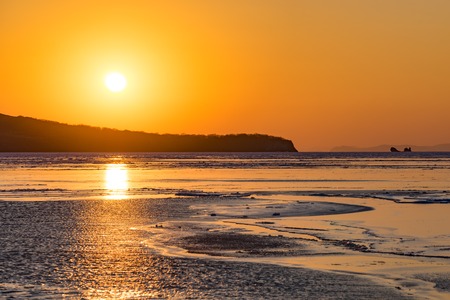 Winter seascape with ice floes on the water surface at sunset. Beauty of nature.の写真素材