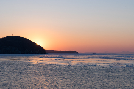 Winter seascape with ice floes on the water surface at sunset. Beauty of nature.の写真素材