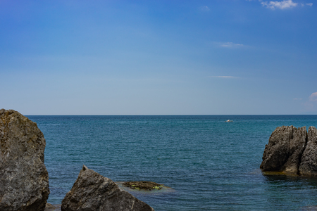 Seascape with a rocky shore line under a blue sky.の写真素材