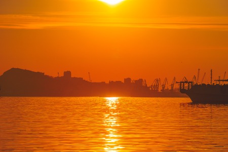 Orange seascape overlooking the dark silhouettes of ships and architecture. Vladivostok, Russia.の写真素材