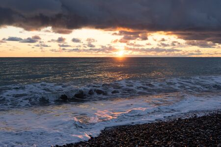 dramatic seascape with dark clouds and sun.の写真素材