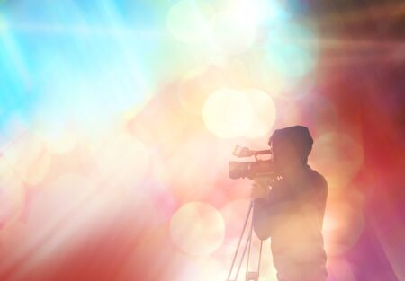 Abstract blurred background with the silhouette of a man. Videographer shoots on video camera.の写真素材