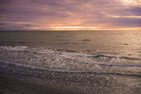 Seascape with a beautiful sunset over the horizon and the water surface.の写真素材