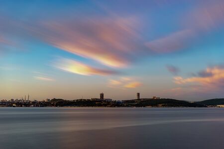 Seascape overlooking the city on the horizon. Charged with long videjko. Beautiful sunset in soft pastel colors. Vladivostok, Russiaの写真素材