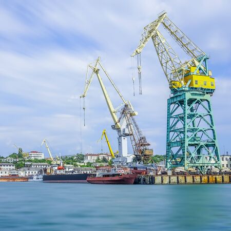 Seascape with the coastline of the port and large floating cranes. The photo was taken at a long exposure. Industrial landscape Sevastopol, Crimea.の写真素材
