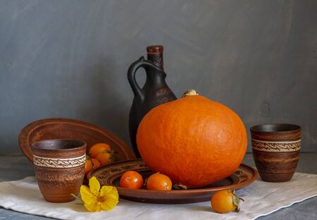 Autumn still life with pumpkin and nasturtium flowers. On the table there is a ceramic tableware and a tablecloth made of natural materials.の写真素材