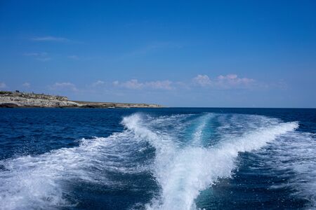 White foam trail from the movement of the boat on a blue background. Travel by sea.の写真素材